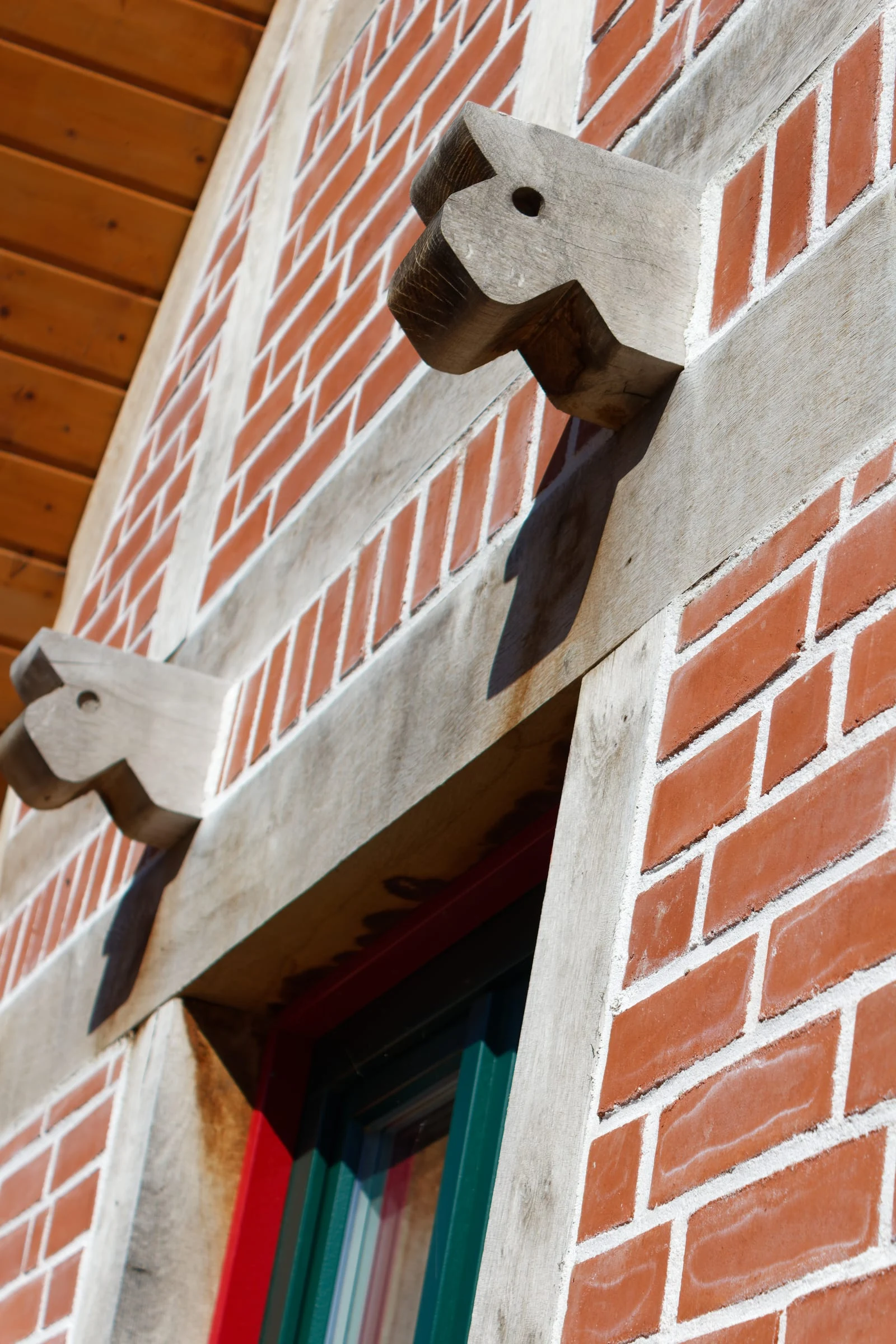 Nahaufnahme von rotem Backstein, hellem Fachwerk und einem grünen Fensterrahmen