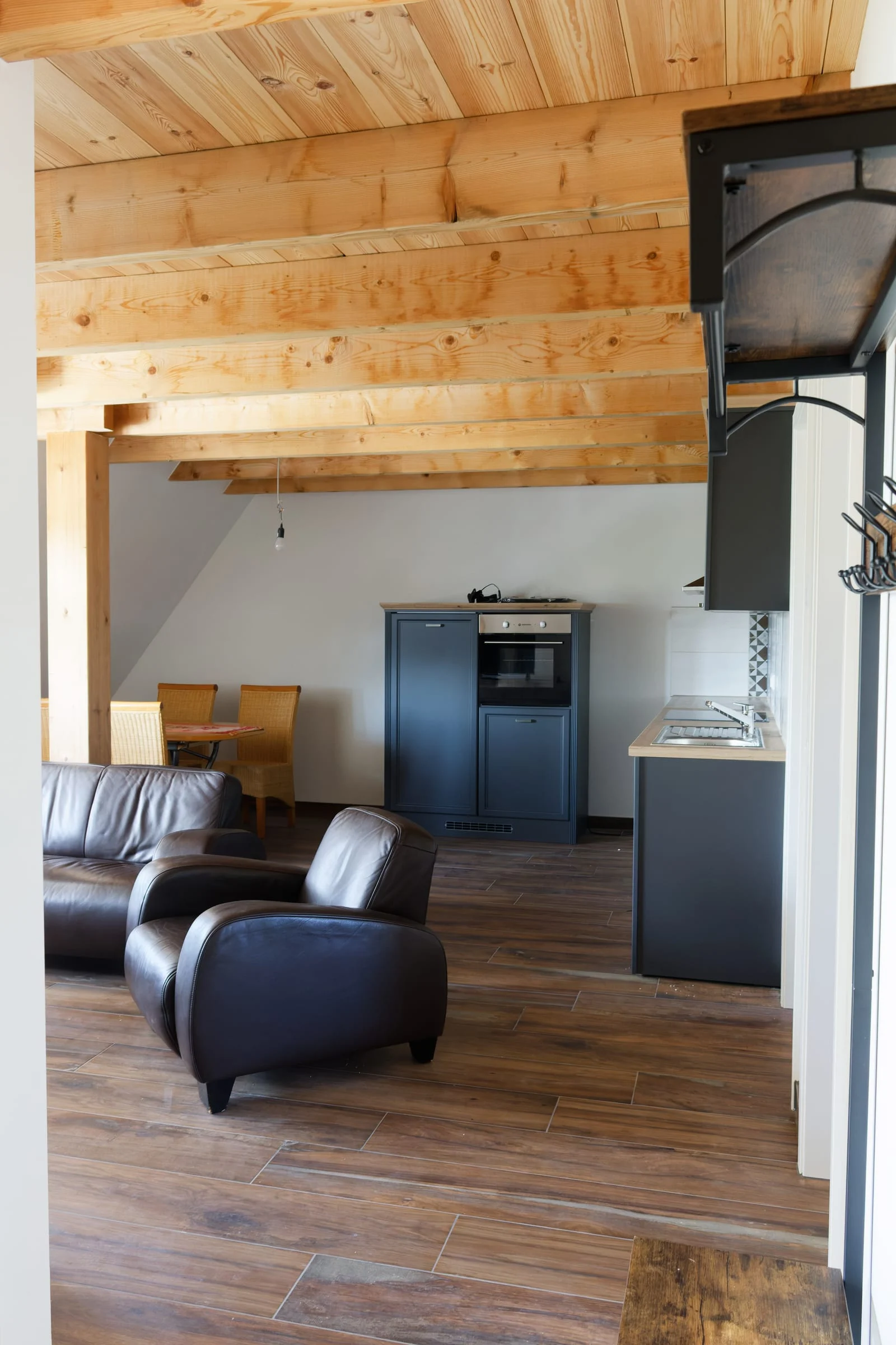 Wohnraum in Ferienwohnung 2 mit Küche, Sitzbereich und offenem Holztragwerk
