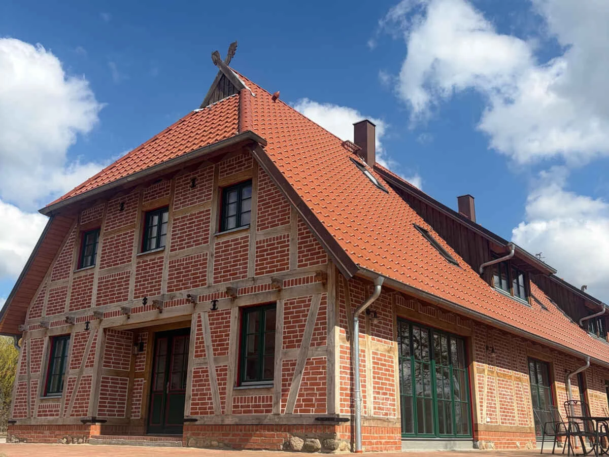 Landhaus Ravensberg mit rotem Ziegeldach, Backsteinfassade, hellem Fachwerk und grünen Fenstern