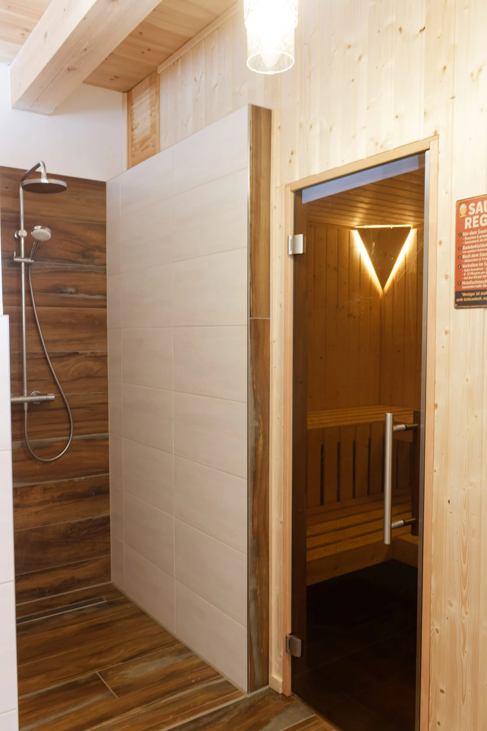 Glastür der privaten Holzsauna neben dem Duschbereich